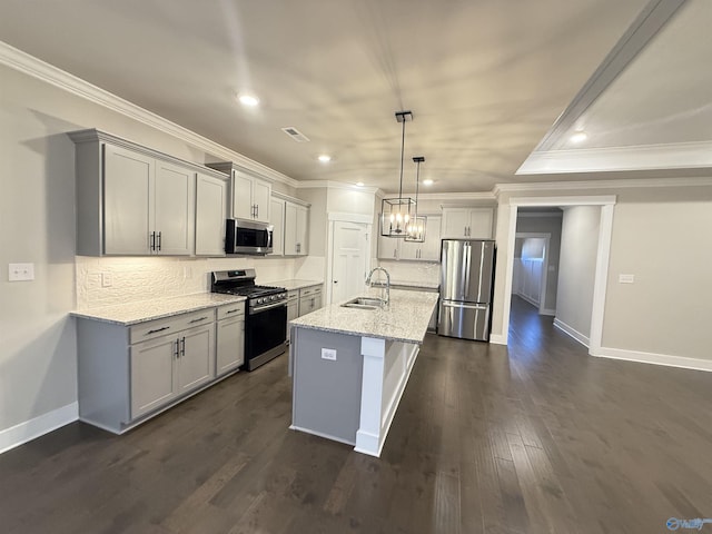 kitchen featuring pendant lighting, sink, appliances with stainless steel finishes, light stone counters, and an island with sink