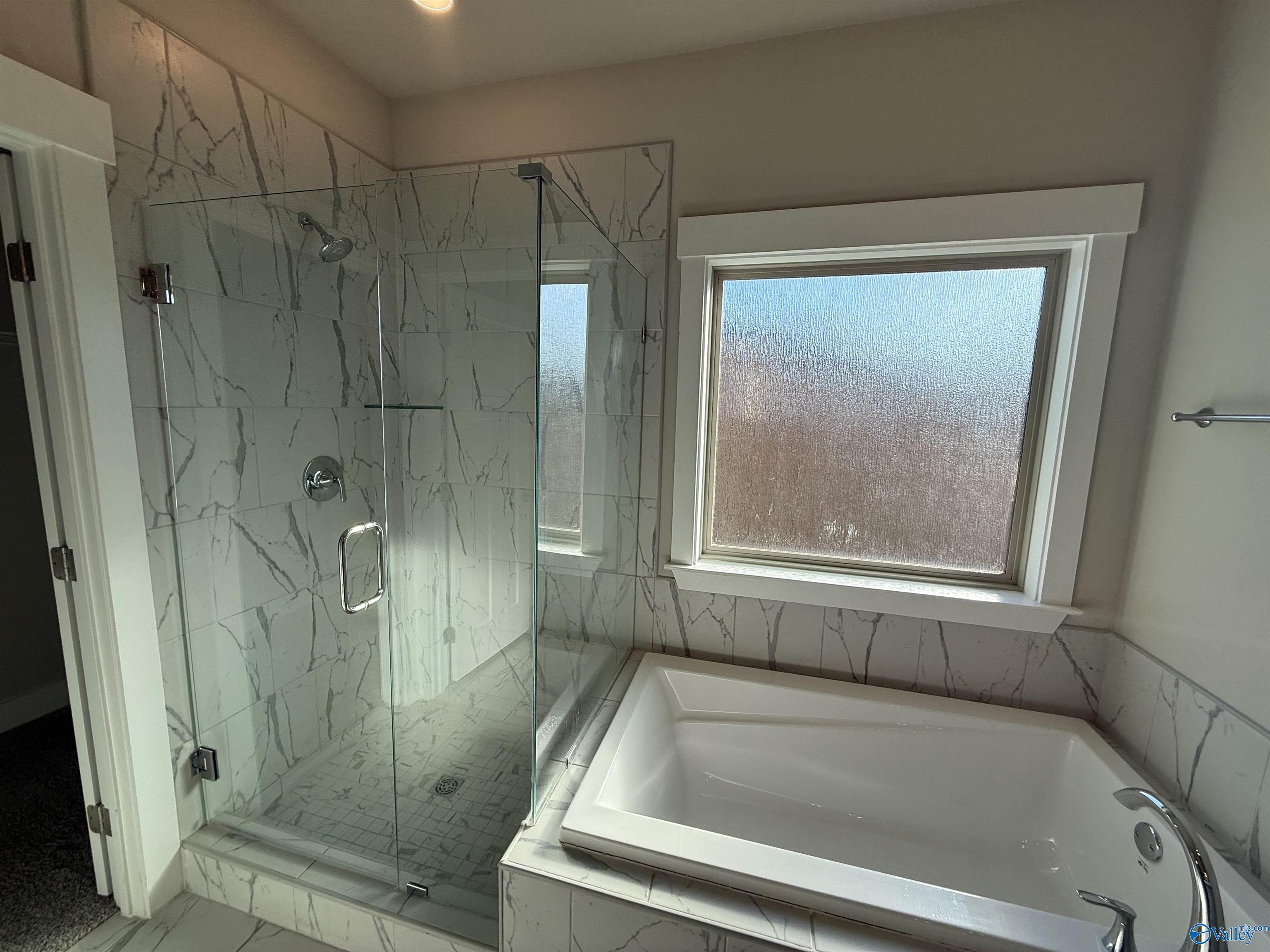 full bathroom featuring a garden tub, a marble finish shower, and marble finish floor