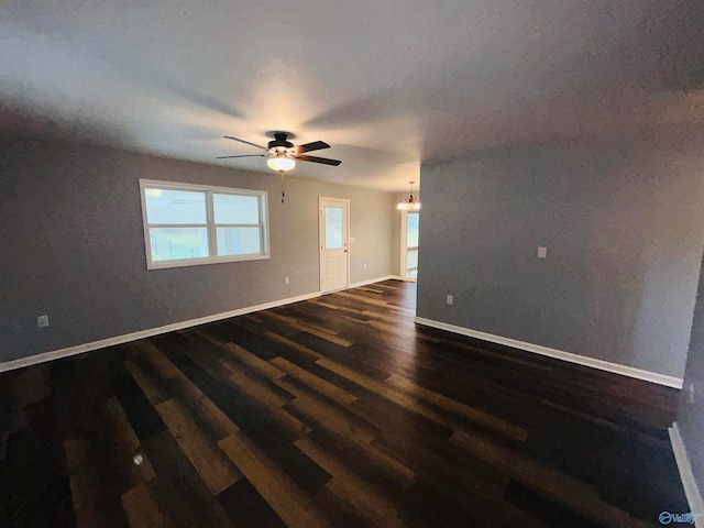 spare room featuring ceiling fan with notable chandelier and dark hardwood / wood-style floors