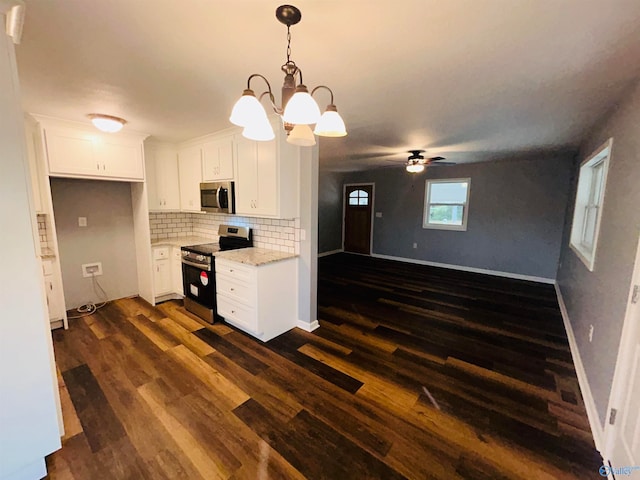 kitchen with hanging light fixtures, dark hardwood / wood-style floors, light stone countertops, white cabinetry, and appliances with stainless steel finishes