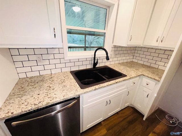 kitchen with decorative backsplash, white cabinetry, stainless steel dishwasher, and sink