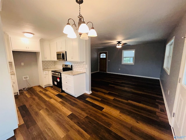 kitchen with light stone counters, appliances with stainless steel finishes, decorative light fixtures, white cabinets, and dark hardwood / wood-style flooring