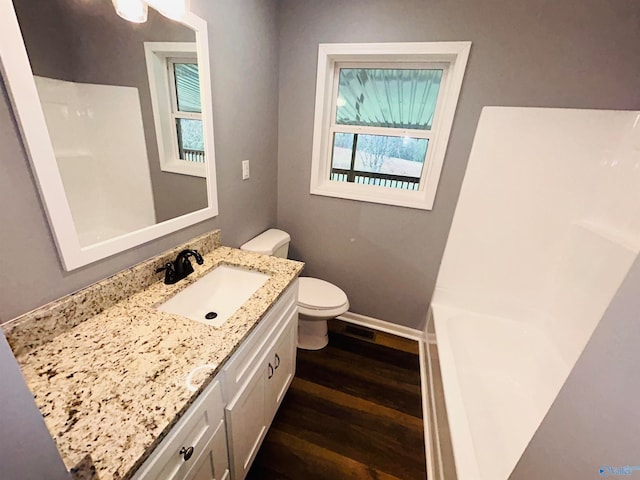 bathroom featuring hardwood / wood-style floors, a tub, vanity, and toilet