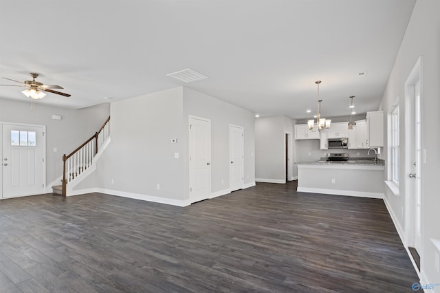 unfurnished living room featuring dark hardwood / wood-style flooring and ceiling fan with notable chandelier