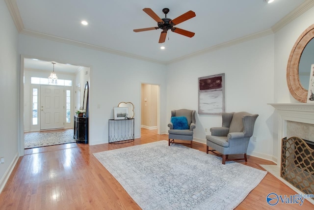 living area with ceiling fan, wood-type flooring, and ornamental molding