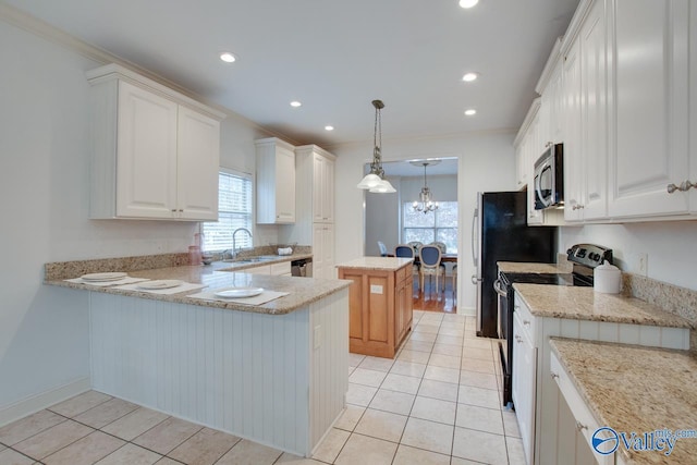 kitchen with kitchen peninsula, appliances with stainless steel finishes, light stone counters, white cabinets, and a kitchen island