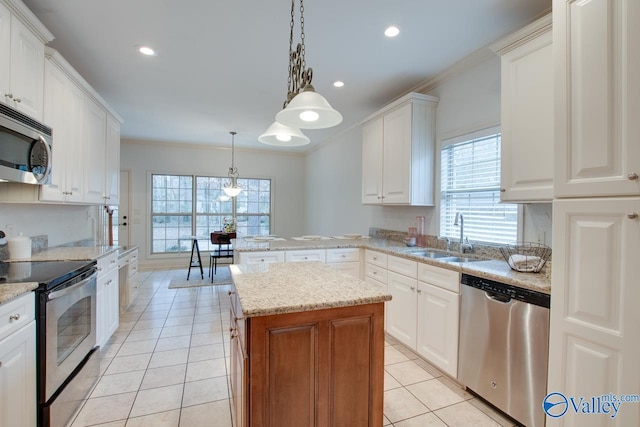 kitchen with a center island, sink, stainless steel appliances, decorative light fixtures, and white cabinets