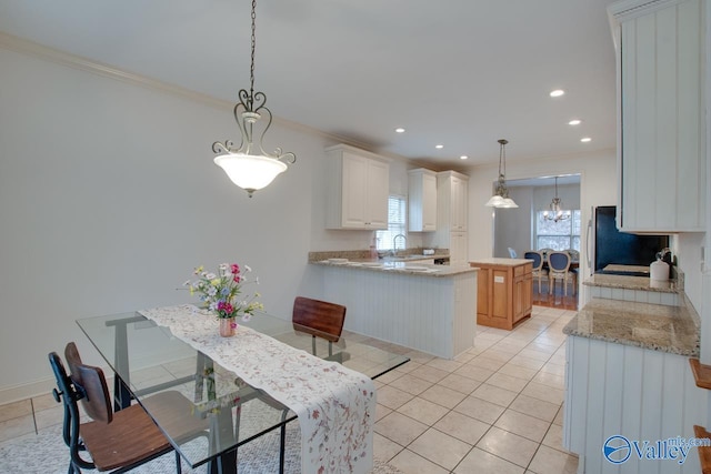 kitchen with kitchen peninsula, white cabinetry, crown molding, and pendant lighting