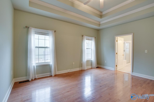 unfurnished room featuring ceiling fan, light hardwood / wood-style flooring, crown molding, and a tray ceiling