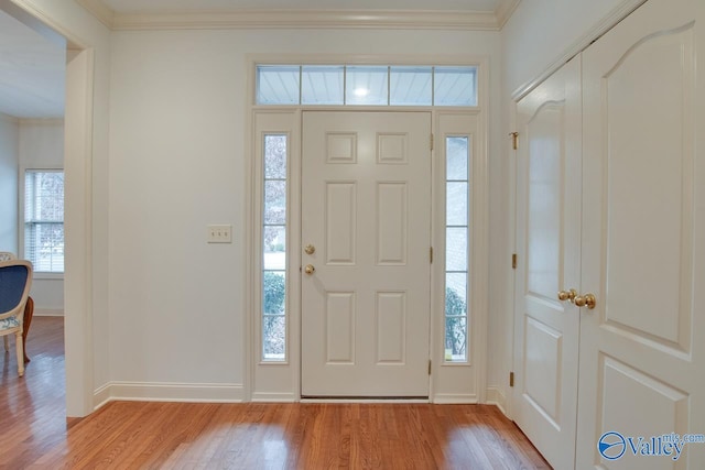 foyer entrance with light hardwood / wood-style floors and crown molding