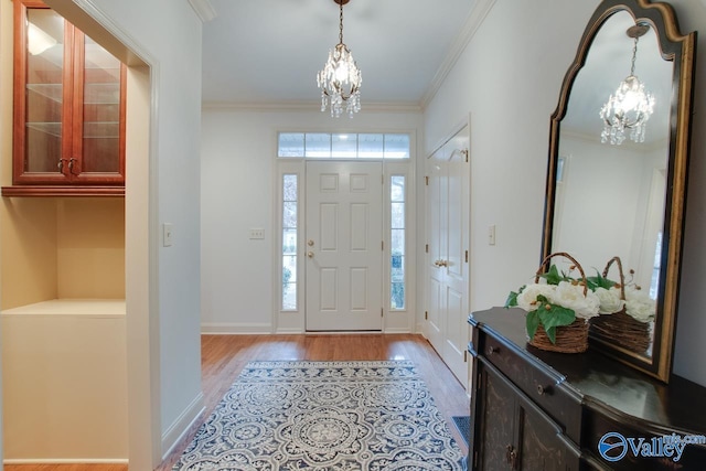 foyer with light hardwood / wood-style flooring, crown molding, and an inviting chandelier