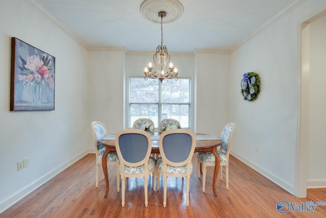 dining room with a chandelier, light hardwood / wood-style flooring, and crown molding