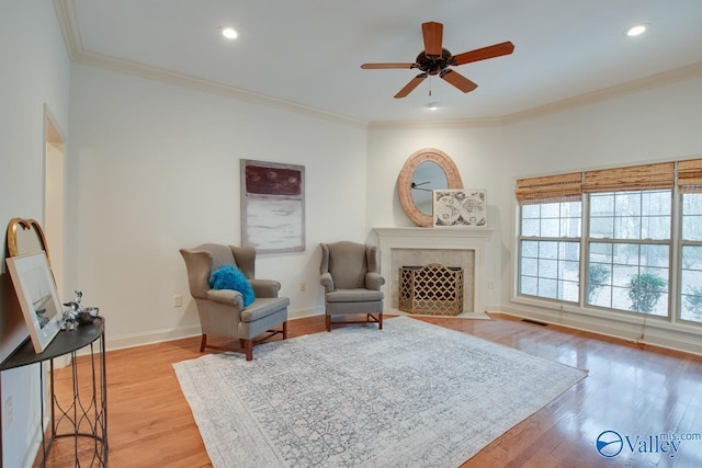 sitting room with light hardwood / wood-style floors, ceiling fan, and crown molding