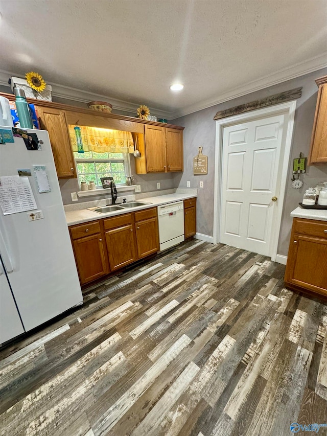 kitchen with sink, crown molding, dark wood-type flooring, and white appliances