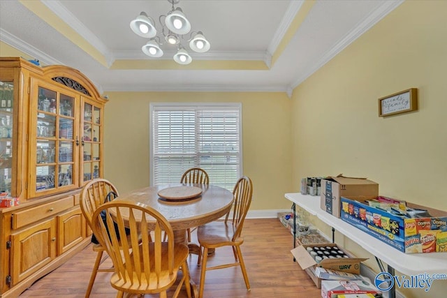 23311 Toone Rd, Elkmont, AL 35620 - dining space featuring a tray ceiling, light wood-type flooring, a notable chandelier, and crown molding