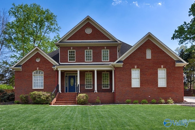 view of front of house featuring brick siding, a front lawn, and a porch