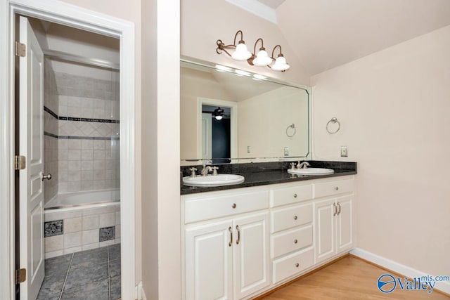 bathroom featuring double vanity, baseboards, a sink, and lofted ceiling
