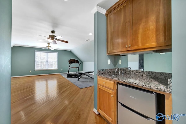 interior space with light wood-type flooring, ceiling fan, baseboards, and vaulted ceiling