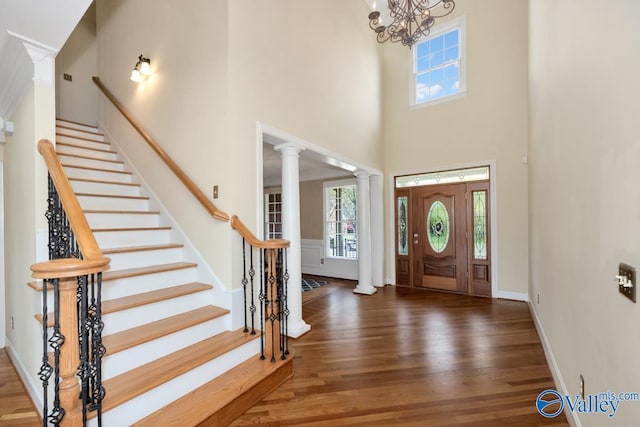 foyer entrance with a high ceiling, wood finished floors, plenty of natural light, and stairway