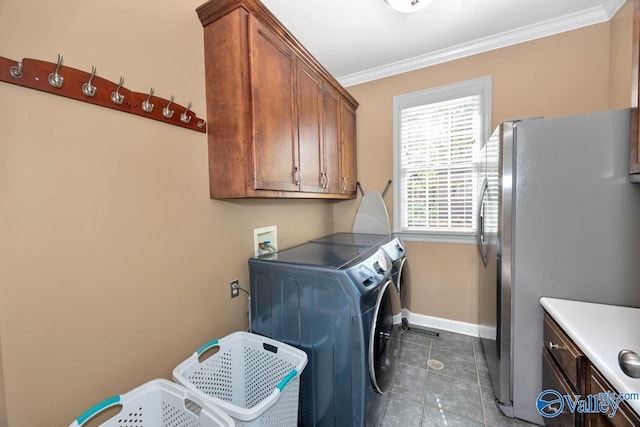 clothes washing area with crown molding, independent washer and dryer, dark tile patterned flooring, baseboards, and cabinet space