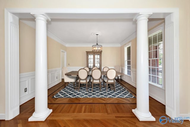dining room with ornate columns, a healthy amount of sunlight, and a wainscoted wall