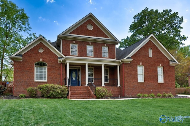 traditional-style home featuring a front yard, brick siding, and covered porch