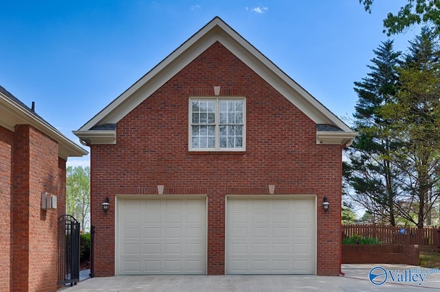 view of side of property with concrete driveway, brick siding, fence, and an attached garage
