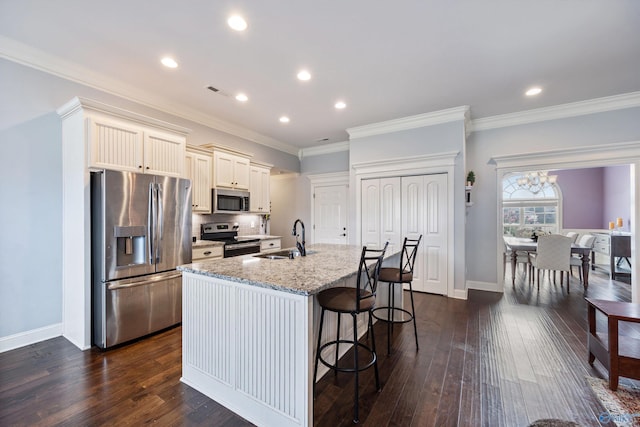 kitchen with stainless steel appliances, sink, light stone counters, dark hardwood / wood-style floors, and a kitchen breakfast bar