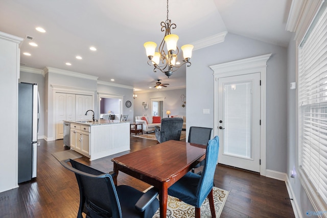 dining area featuring dark wood-type flooring, sink, crown molding, vaulted ceiling, and ceiling fan with notable chandelier