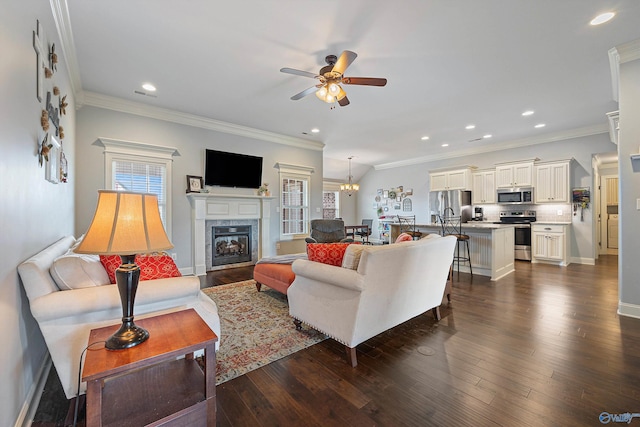 living room featuring a fireplace, ornamental molding, dark hardwood / wood-style flooring, and ceiling fan with notable chandelier