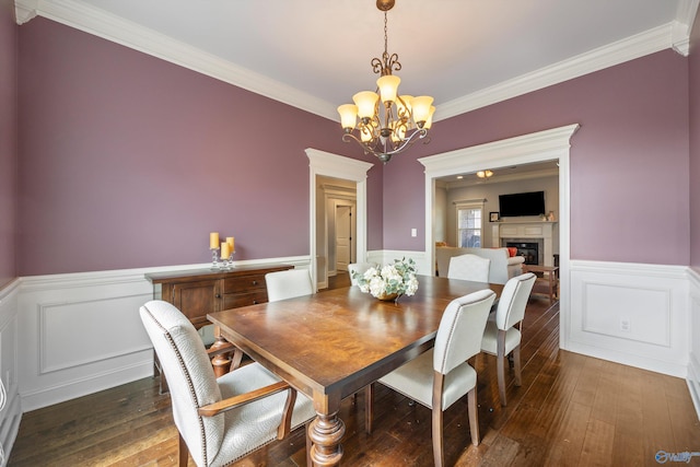 dining area with an inviting chandelier, dark wood-type flooring, and crown molding