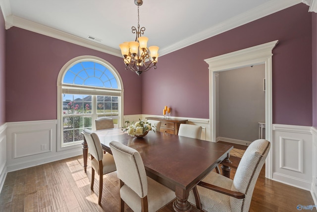 dining area featuring an inviting chandelier, ornamental molding, and wood-type flooring