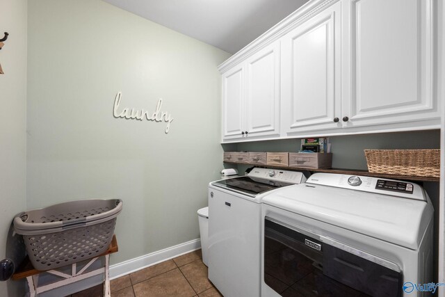 washroom with baseboards, cabinet space, tile patterned flooring, and washing machine and dryer