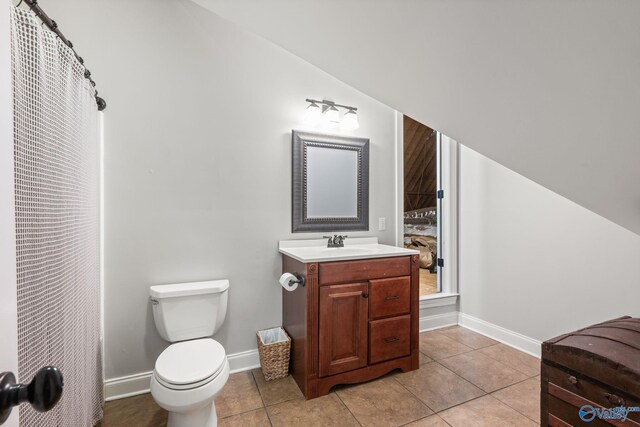 bathroom featuring lofted ceiling, vanity, toilet, and tile patterned floors