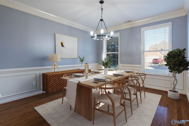 dining area with ornamental molding, wood-type flooring, and an inviting chandelier