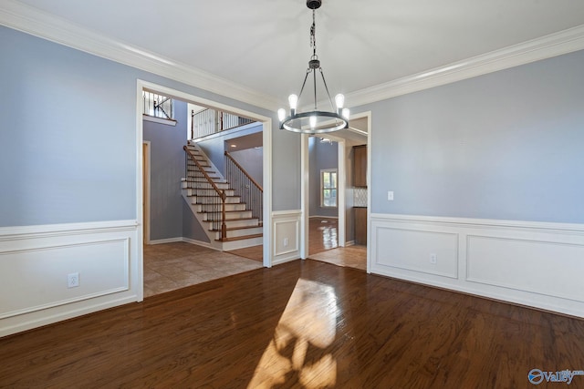 unfurnished dining area with a notable chandelier, ornamental molding, and wood-type flooring