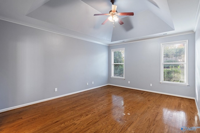 spare room with ornamental molding, ceiling fan, wood-type flooring, and a raised ceiling