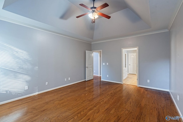 unfurnished bedroom with ceiling fan, a tray ceiling, wood-type flooring, and ornamental molding