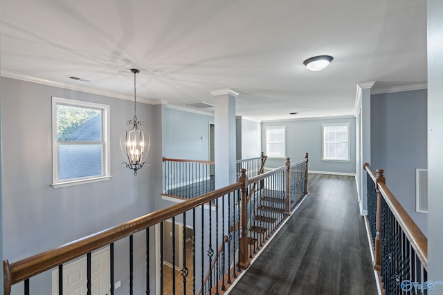 hallway featuring ornamental molding, decorative columns, a notable chandelier, and dark hardwood / wood-style floors