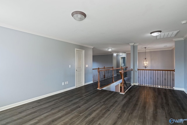 spare room with ornamental molding, decorative columns, a notable chandelier, and dark hardwood / wood-style floors