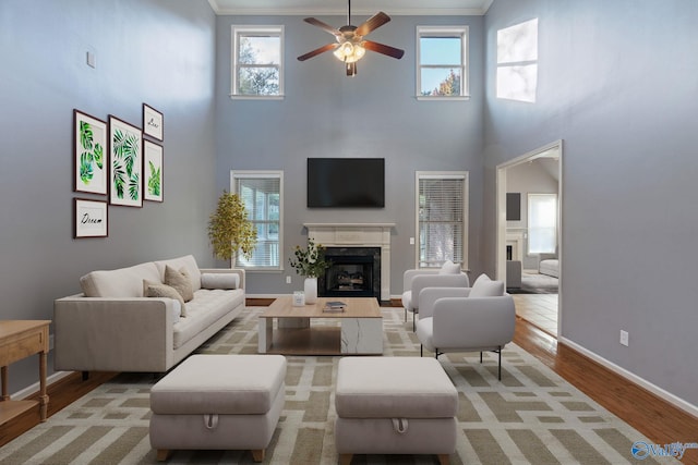 living room featuring a towering ceiling, crown molding, a healthy amount of sunlight, and hardwood / wood-style flooring