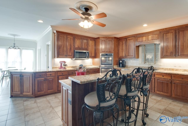 kitchen featuring a kitchen island, appliances with stainless steel finishes, brown cabinets, and crown molding