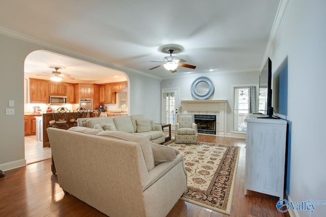 living area featuring arched walkways, ornamental molding, and a healthy amount of sunlight