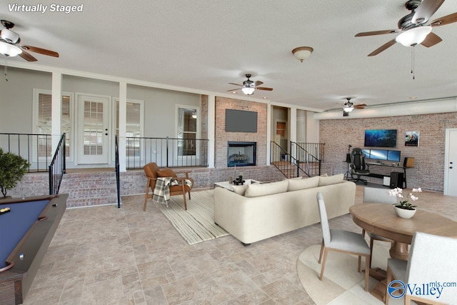 living area featuring a textured ceiling, brick wall, a fireplace, and stone finish flooring