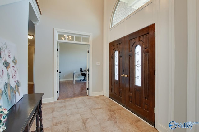 entryway featuring a towering ceiling and baseboards