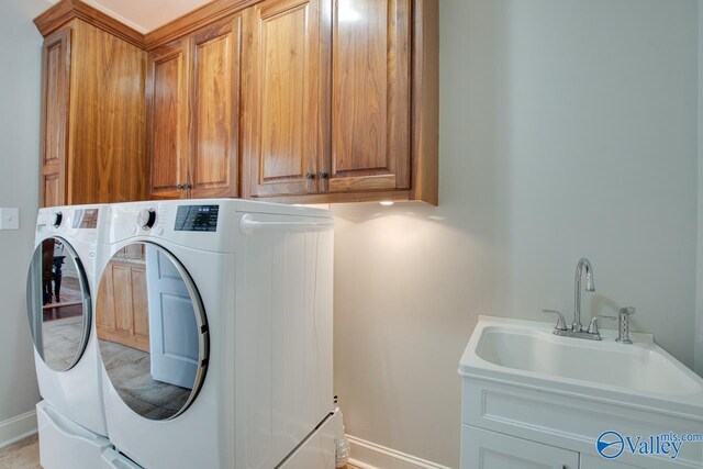 washroom featuring baseboards, cabinet space, independent washer and dryer, and a sink