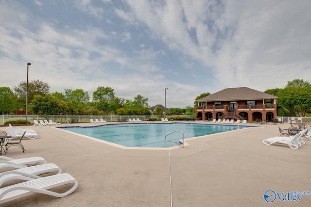 community pool with a patio area and fence