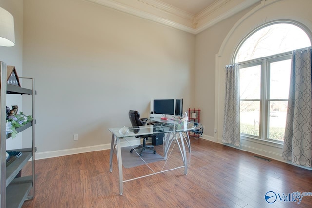 office space with visible vents, crown molding, baseboards, and wood finished floors