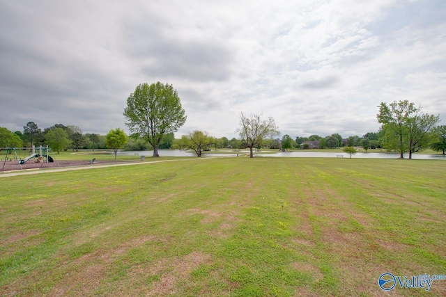 view of property's community with playground community, a yard, and a water view