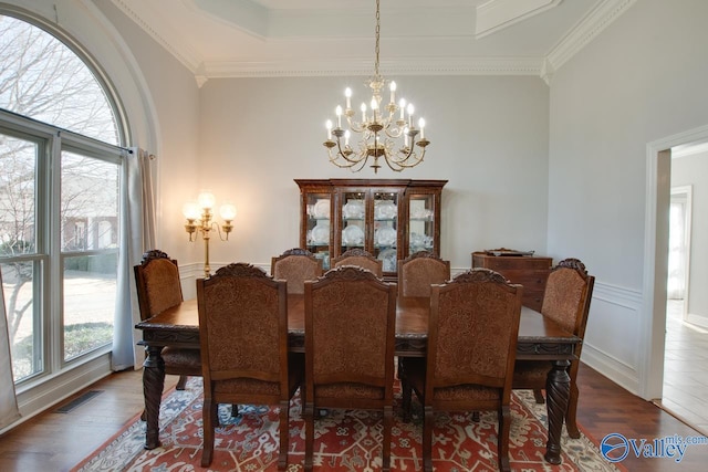 dining room featuring visible vents, wood finished floors, and ornamental molding